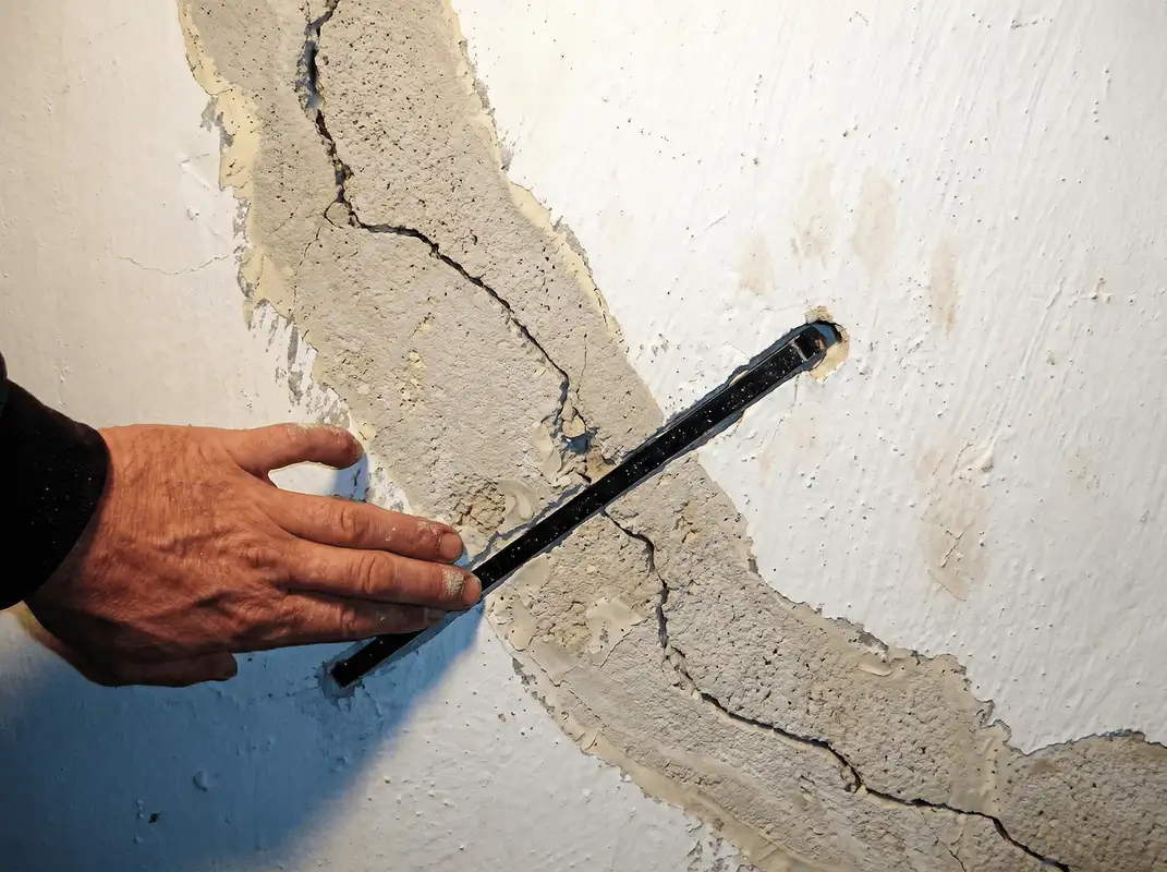 A wall with a large crack is being inspected by a professional in Omaha, NE
